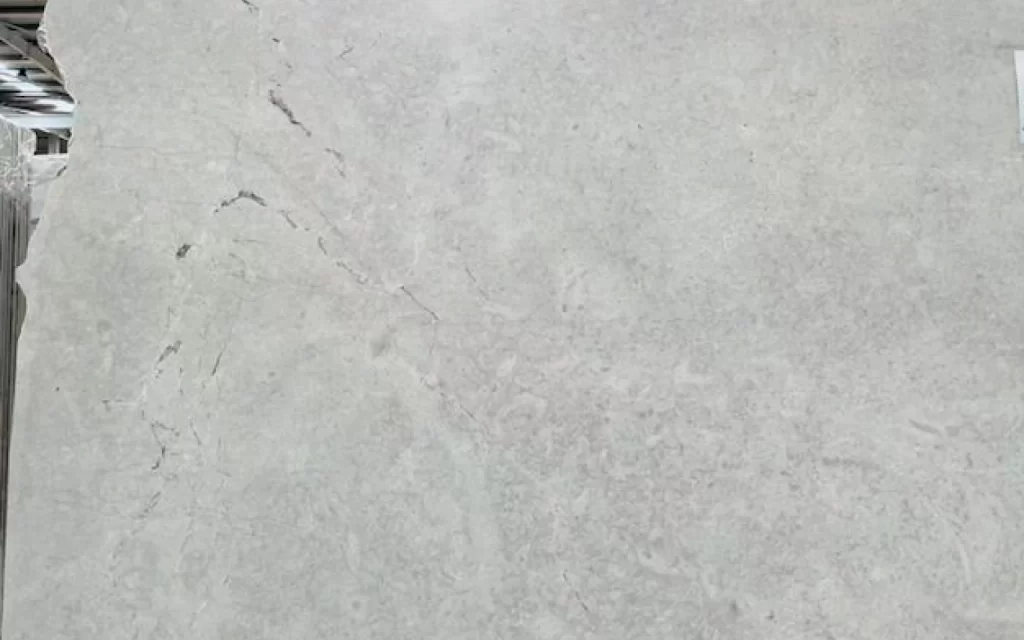 A gray marble slab with subtle white veins and slight cracks visible on the surface.