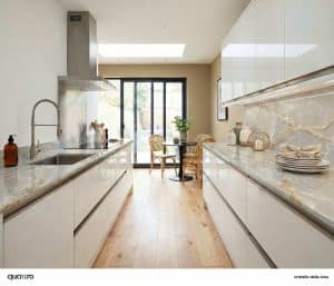 Modern kitchen with glossy white cabinets, Cristello Della Luna marble countertops, and light wood flooring; dining table with chairs near large glass doors to the outside.